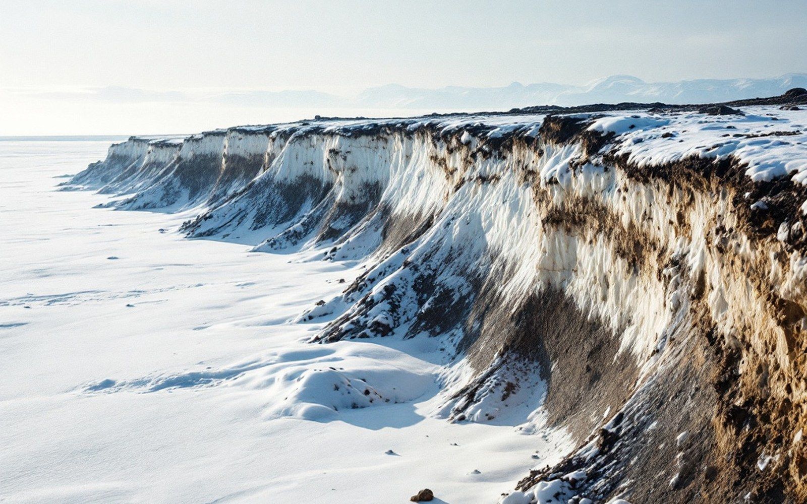 An undercut bank of frozen soil above a beach