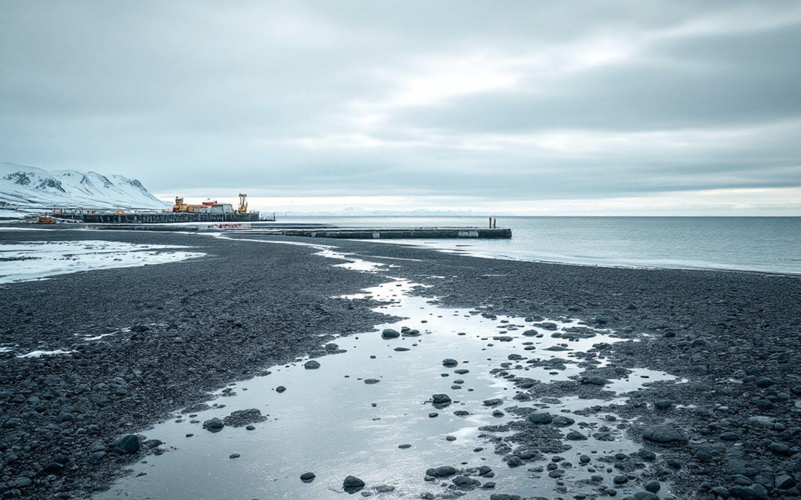 A shallow shoreline with a jetty and open sea beyond