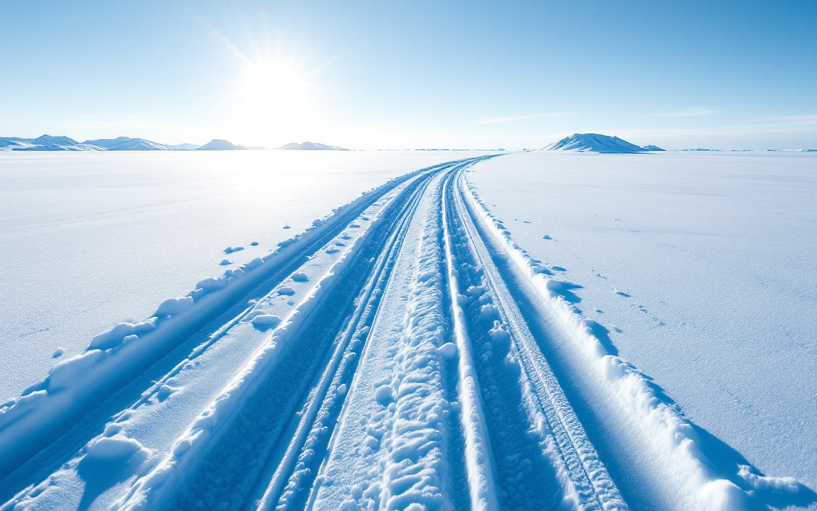 A single narrow snowmachine track curving away over unbroken snow seen from low down, long blue shadows, no road and no vehicle