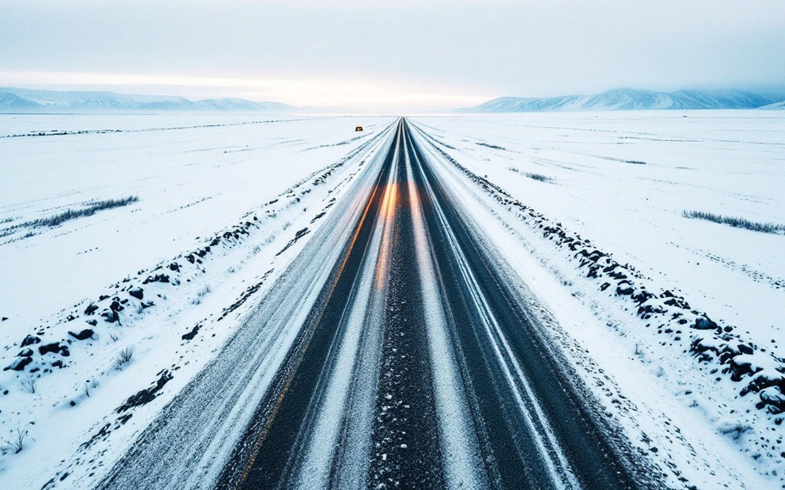A gravel haul road running straight across tundra