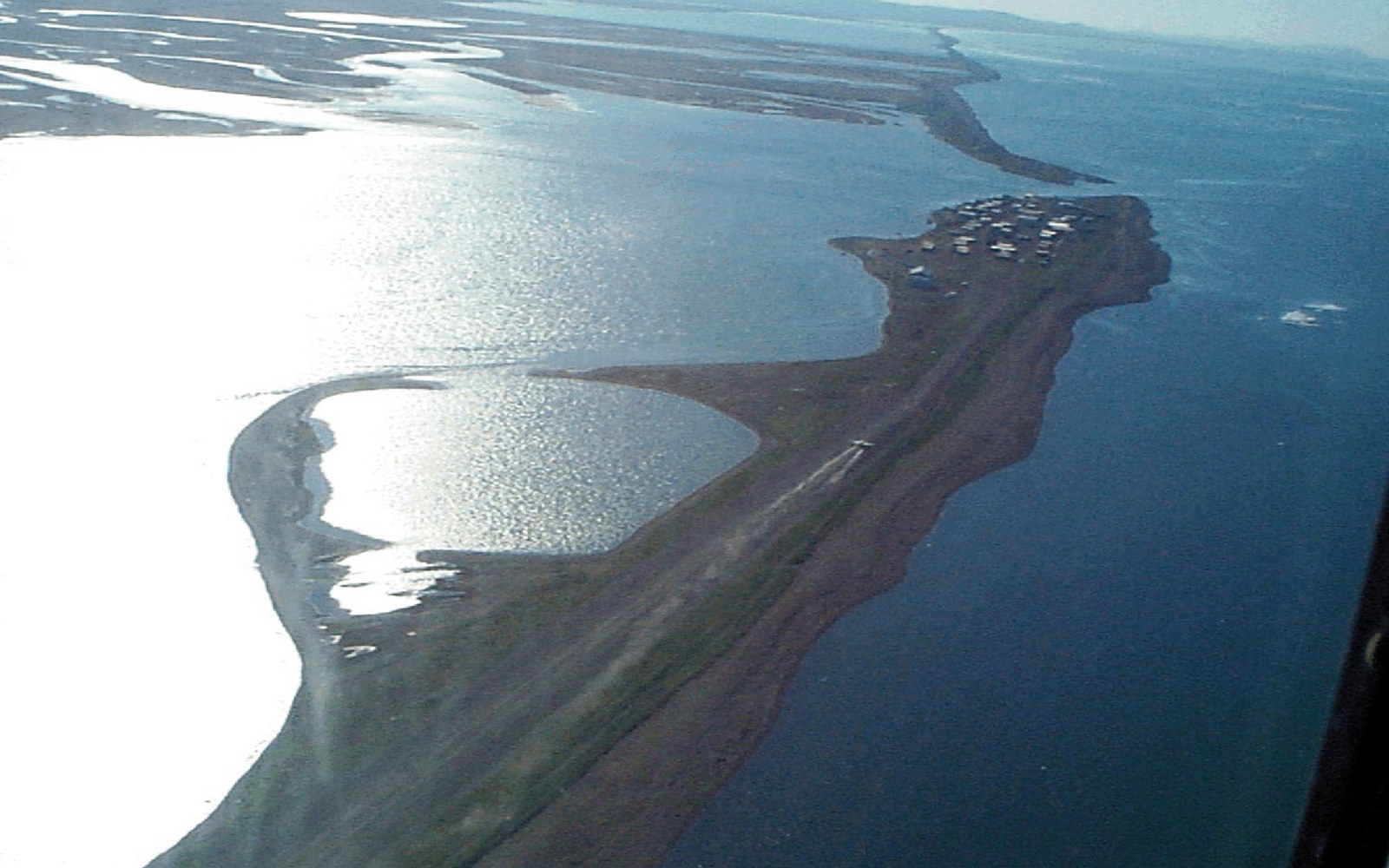 Aerial view of a narrow barrier island village between a lagoon and the sea